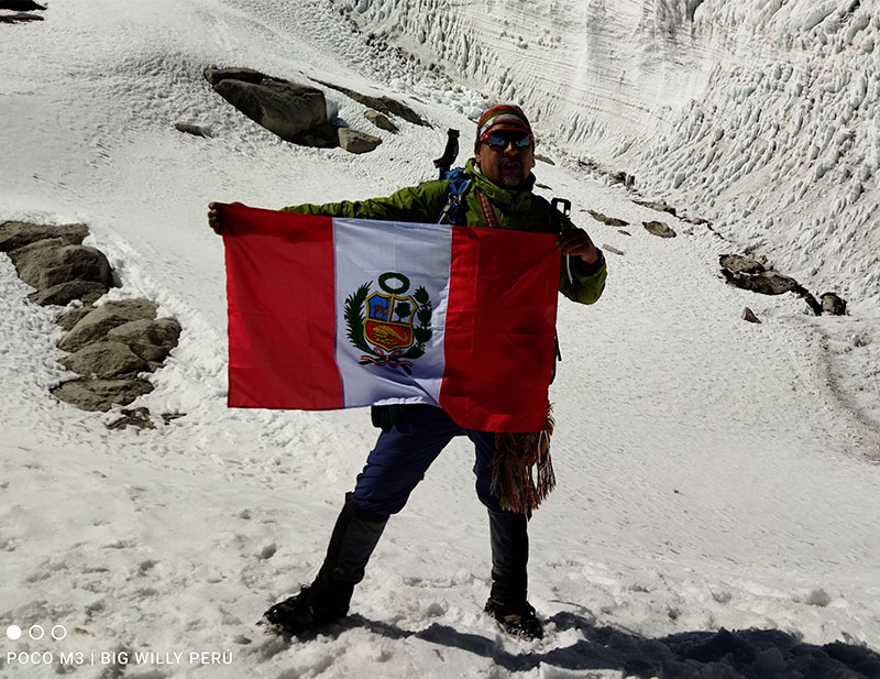 A man in the snow with the flag of peru